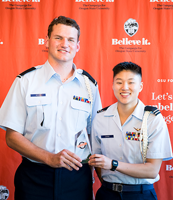 Two people holding a dammy award and smiling.