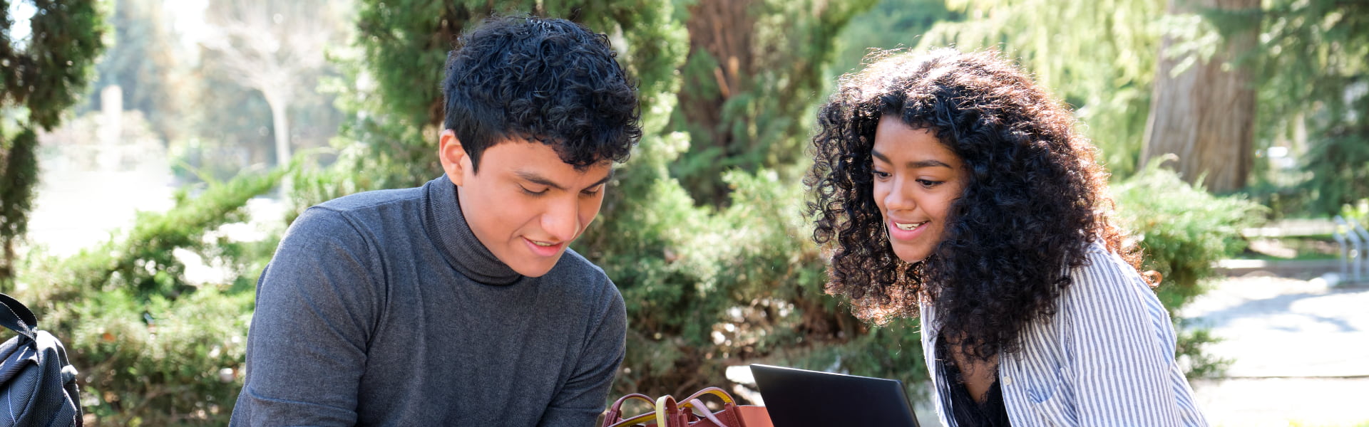 Students outdoors studying with a laptop