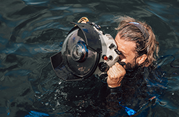 SCUBA diver at the surface of the ocean using a tool