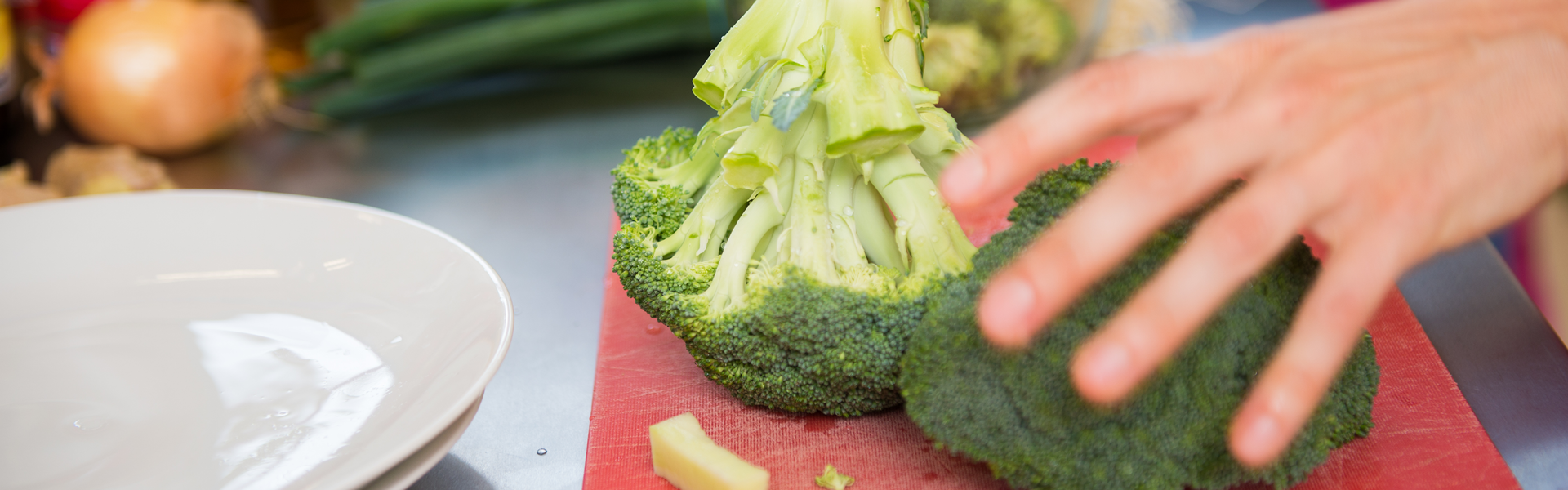 person holding broccoli on a cutting board to prepare it for cooking