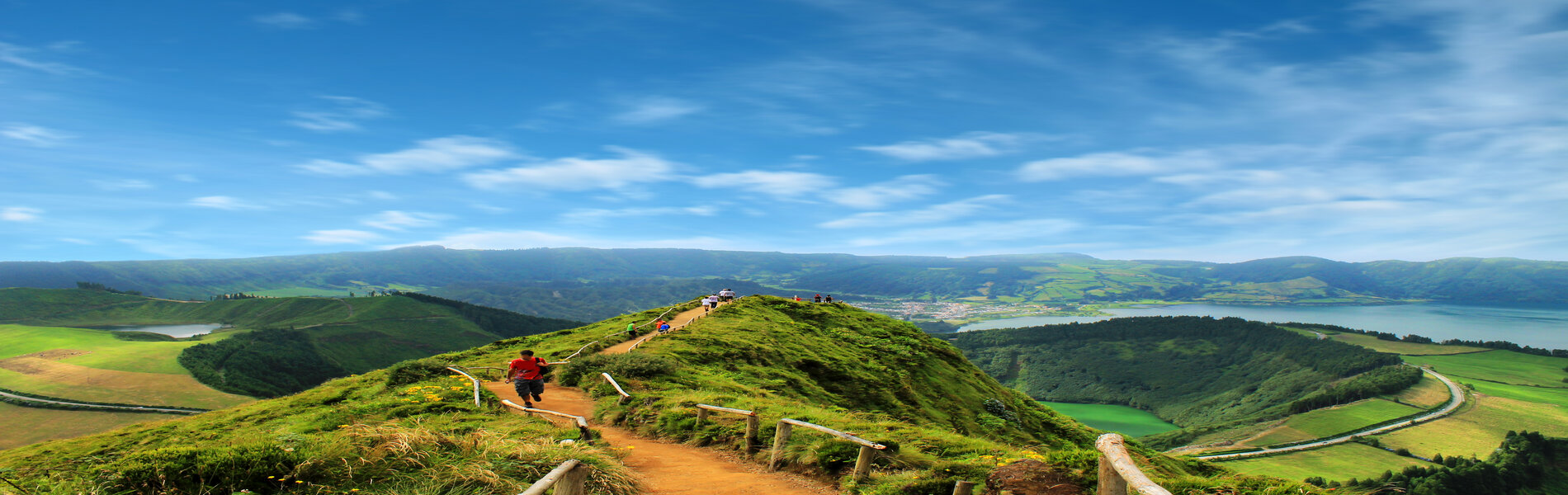 Hikers at the top of a steep mountain overlooking a lake and other mountains