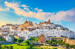 Ostuni buildings with green grass and blue skies with scattered clouds