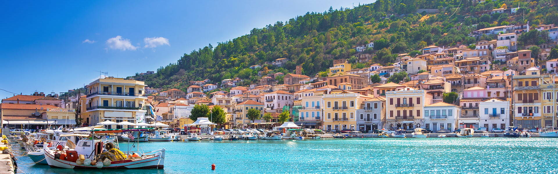 Gytheio coast with bright blue waters, blue skies and colorful buildings on the coast