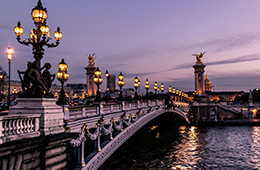 Paris bridge covered in lampposts with river below at sunset