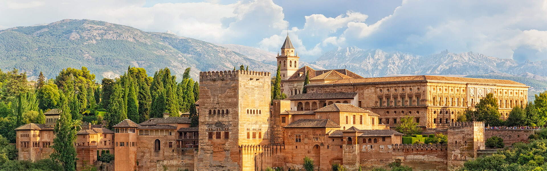 Alhambra palace in Spain, with green treea and mountains in the background