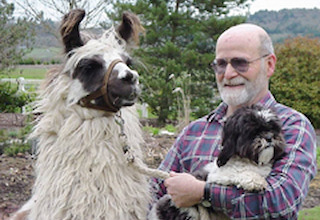 Glen Pfefferkorn with one of his llamas and holding his dog