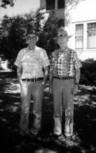 Andrew and Robert Morrow standing outside in front of a house, in black and white