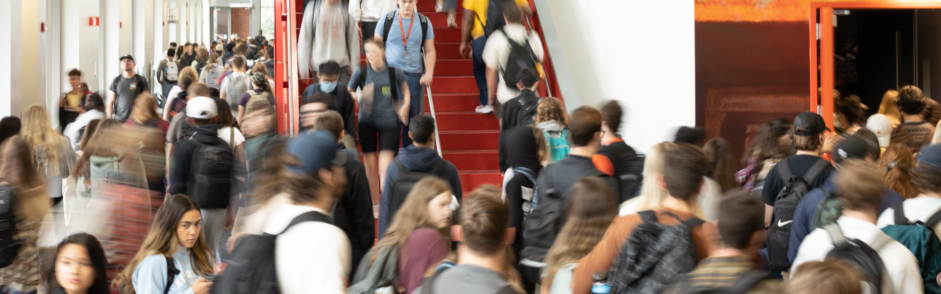 A crowded hall and stairway filled with students wearing backpacks.