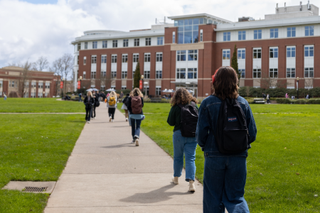 A line of students walking on a sideway towards the library.