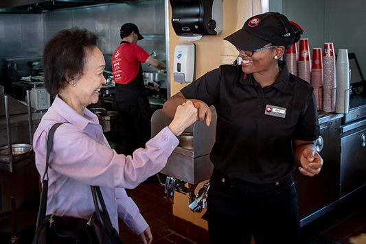 two women in commercial kitchen doing a fist bump