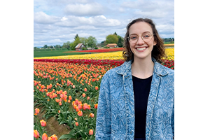 Malory_300x200 Malory Turner smiling in front of multicolored rows of tulips.