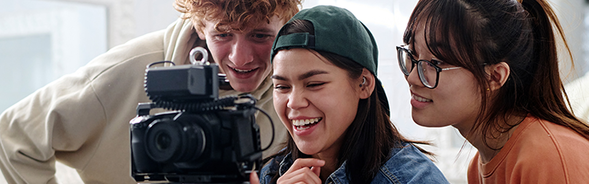 Three people looking at the display on a camera.