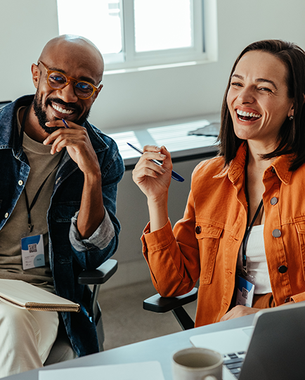 Colleagues laugh in an office setting.