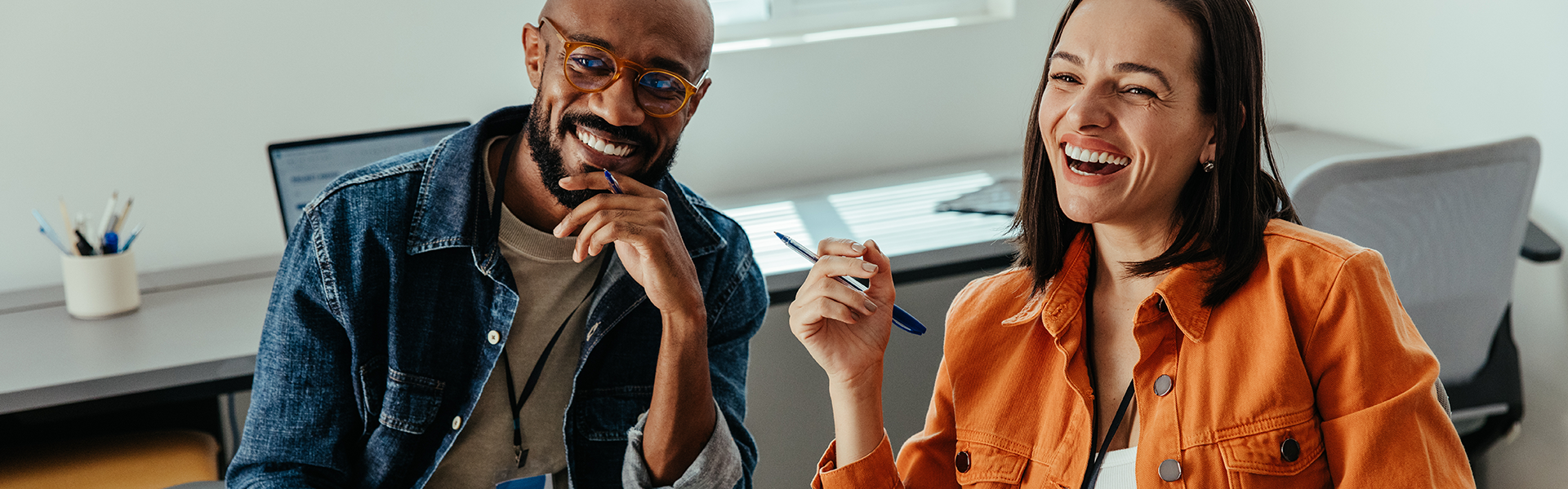 Colleagues laugh in an office setting.