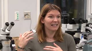 woman speaking with laboratory equipment in background speaking of knowledge of sea floor