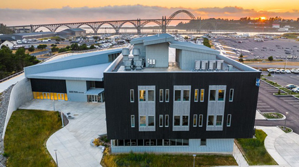 Aerial view of the Gladys Valley Marine Studies Building with Newport, ocena and bridge in the background at sunset