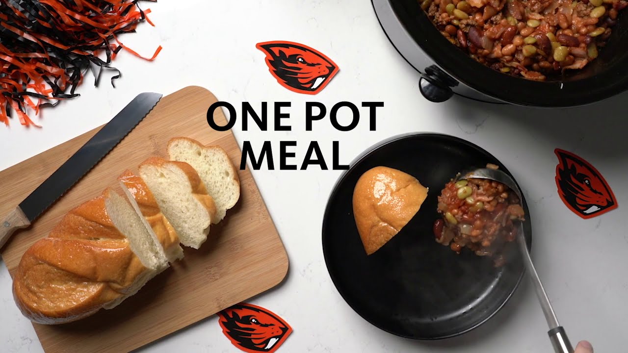 "One Pot Meal" bread cut on a cutting board, with a one pot meal in a large pot with a plate